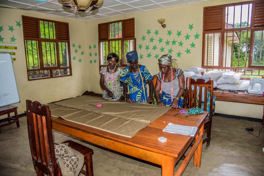 Three women at a fabric cutting table